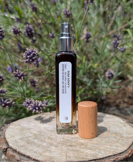 Bottle of candy pine botanical spray perfume with wooden cap on a wooden stump with lavender in the background
