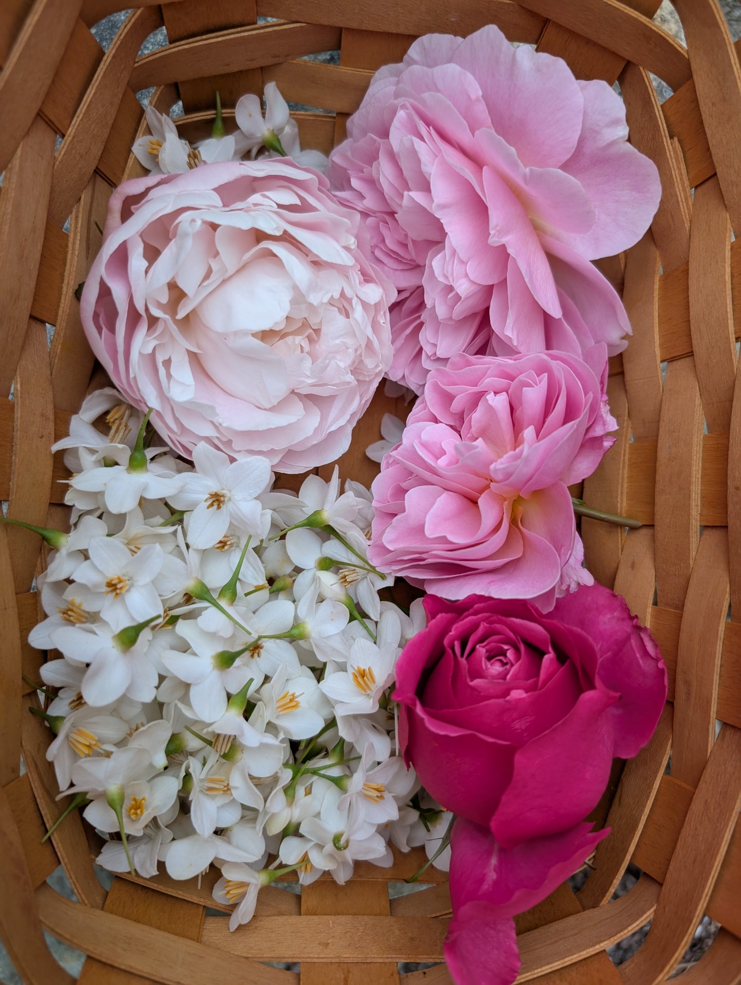 Assorted pink and white flowers in a woven basket